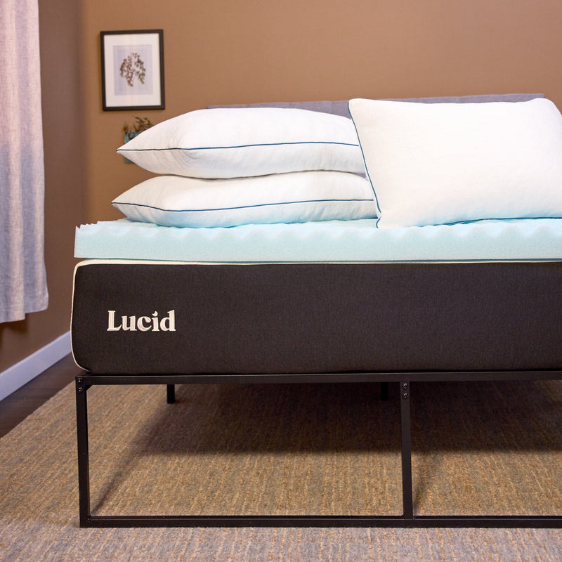 Bed with Lucid mattress and bedding in a room with a brown wall and framed picture.
